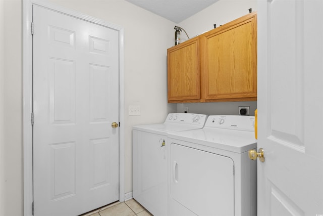 clothes washing area with cabinet space, washer and dryer, and light tile patterned floors