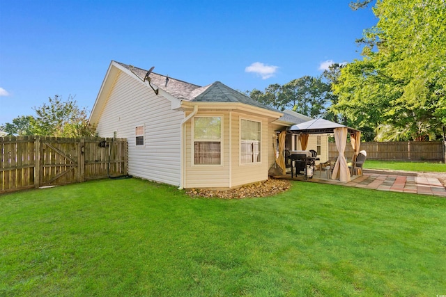 rear view of property with a gazebo, a patio area, a shingled roof, and a gate