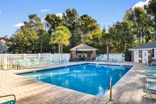 community pool with a patio, fence, and a gazebo