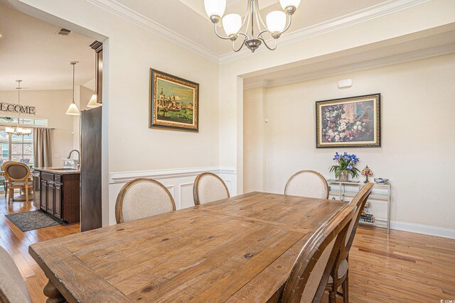 967 Henry James Dr, Myrtle Beach, SC 29579 - dining area with a chandelier, light wood-type flooring, crown molding, a wainscoted wall, and baseboards