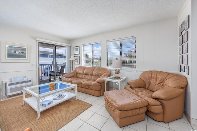 living area featuring a wall mounted AC, light tile patterned floors, and a textured ceiling