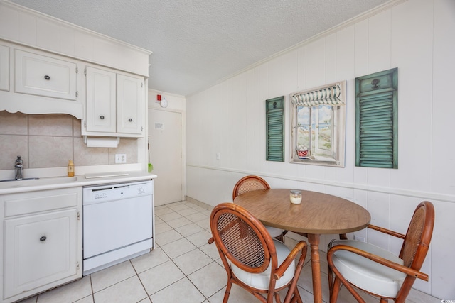 kitchen with white dishwasher, a sink, crown molding, light countertops, and white cabinetry