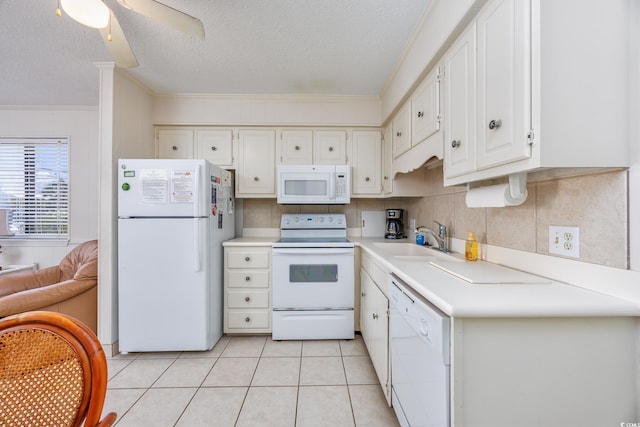kitchen with white appliances, a sink, ornamental molding, a textured ceiling, and white cabinets