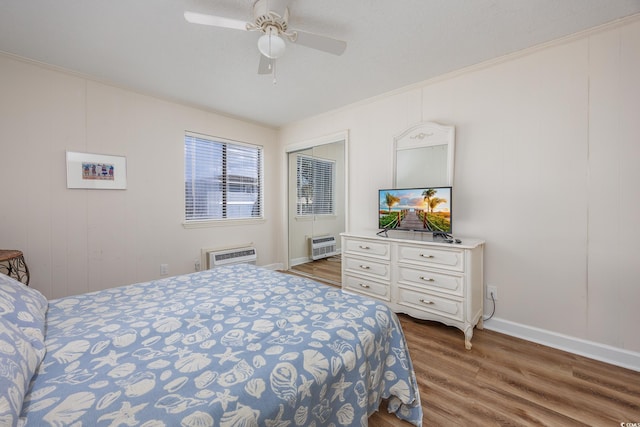 bedroom featuring wood finished floors, baseboards, a ceiling fan, crown molding, and a closet