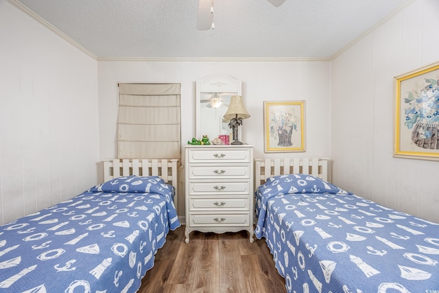 bedroom with crown molding, wood finished floors, a textured ceiling, ceiling fan, and wood walls