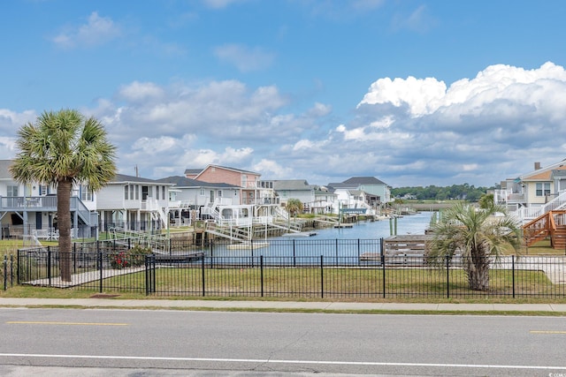water view with nearby suburban area, fence, and a boat dock