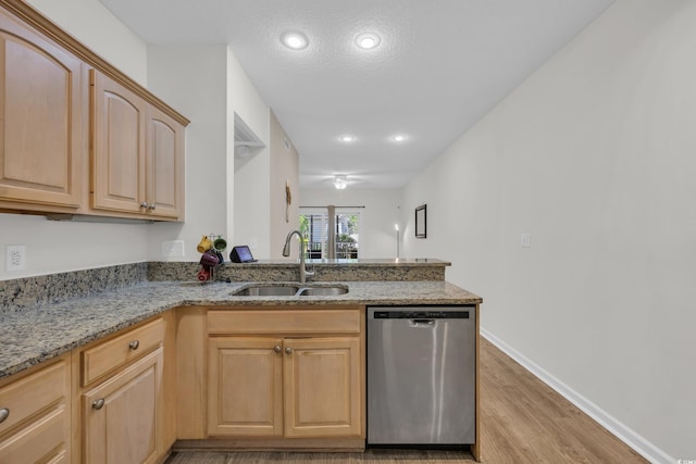 kitchen featuring dishwasher, a sink, light brown cabinets, light wood-type flooring, and light stone countertops