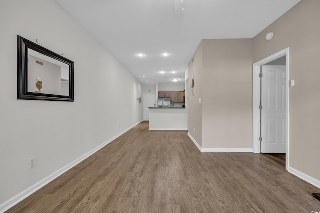 unfurnished living room featuring wood finished floors, baseboards, and recessed lighting