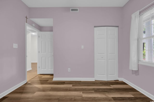 unfurnished bedroom featuring wood finished floors, baseboards, and a closet