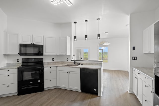 kitchen with black appliances, a sink, a peninsula, light wood-style flooring, and white cabinetry