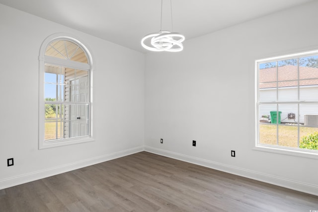spare room with a chandelier, wood finished floors, and baseboards