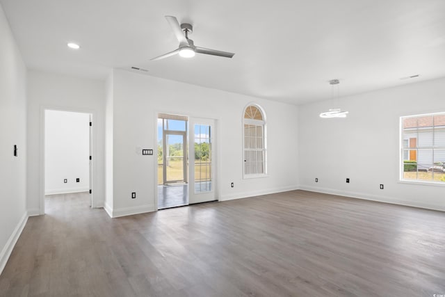 unfurnished living room with plenty of natural light, a ceiling fan, wood finished floors, baseboards, and recessed lighting