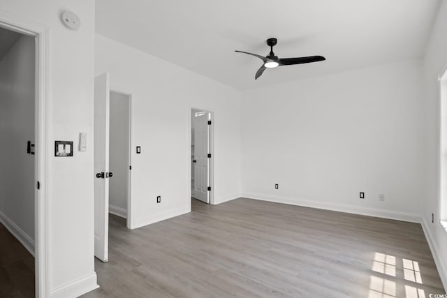 empty room featuring ceiling fan, wood finished floors, and baseboards