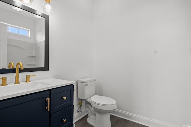 bathroom featuring baseboards, wood finished floors, toilet, and vanity