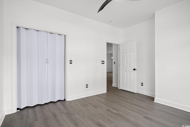 unfurnished bedroom featuring wood finished floors, baseboards, a ceiling fan, and a closet