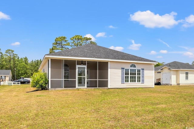 back of property featuring a sunroom, a yard, and roof with shingles