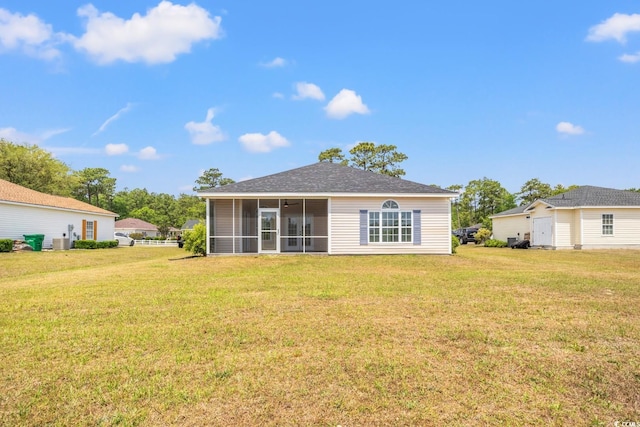 back of property with a yard, a sunroom, a shingled roof, and central AC