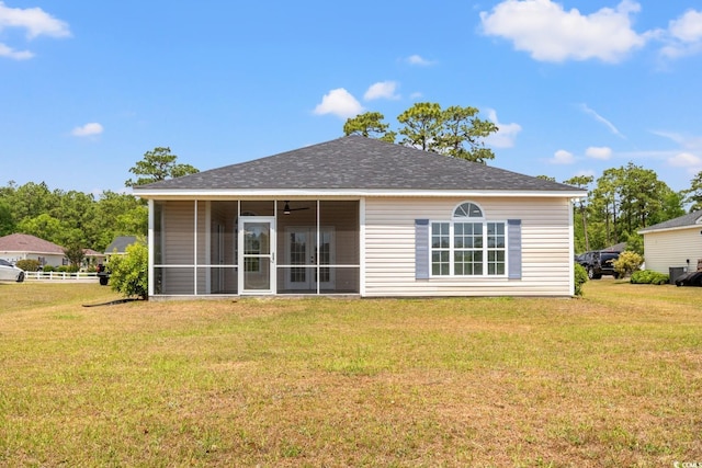rear view of property featuring a yard, a sunroom, and a shingled roof