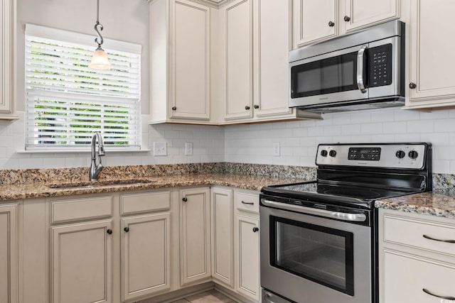 kitchen with appliances with stainless steel finishes, a sink, backsplash, and pendant lighting