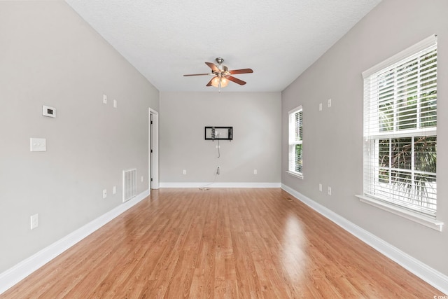 unfurnished living room with ceiling fan, light wood-style flooring, baseboards, and a textured ceiling