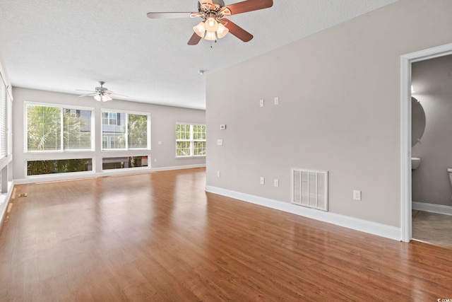 unfurnished living room featuring ceiling fan, wood finished floors, baseboards, and a textured ceiling