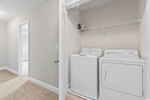 laundry room featuring washing machine and dryer, light colored carpet, and baseboards
