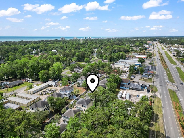 drone / aerial view of a major roadway, a nearby body of water, and a tree filled landscape