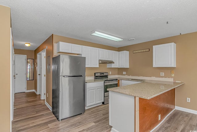 kitchen with appliances with stainless steel finishes, under cabinet range hood, light wood-style flooring, a peninsula, and white cabinetry