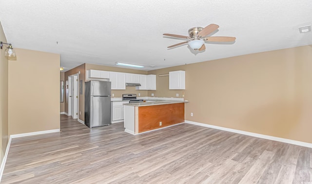 kitchen featuring appliances with stainless steel finishes, open floor plan, under cabinet range hood, light wood finished floors, and a textured ceiling