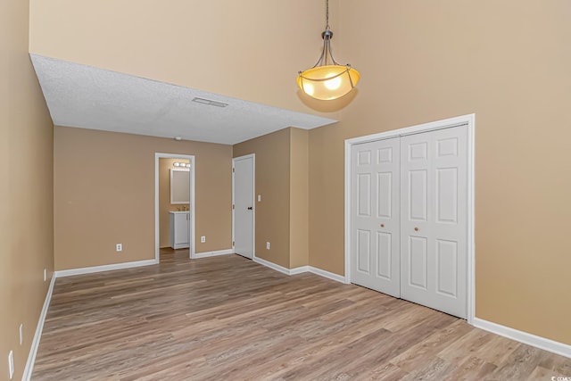unfurnished room with light wood-type flooring, baseboards, and a textured ceiling