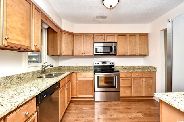 816 Kittiwake Ln, Murrells Inlet, SC 29576 - kitchen featuring stainless steel appliances, a sink, light wood finished floors, light stone countertops, and a textured ceiling