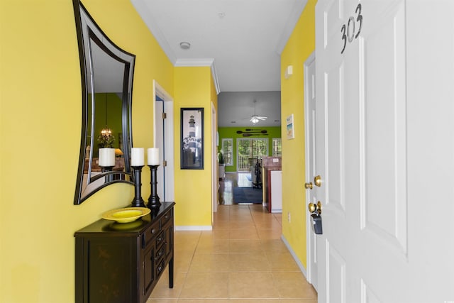 corridor featuring baseboards, light tile patterned flooring, and crown molding