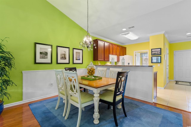 dining room featuring light wood finished floors, a chandelier, baseboards, ornamental molding, and a towering ceiling