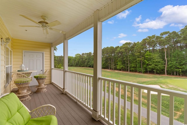 wooden terrace featuring ceiling fan and a yard