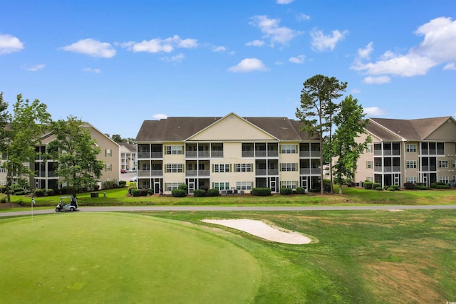 view of home's community with view of golf course, an area to practice putting, and a lawn