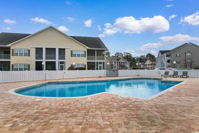 community pool with a patio area and fence