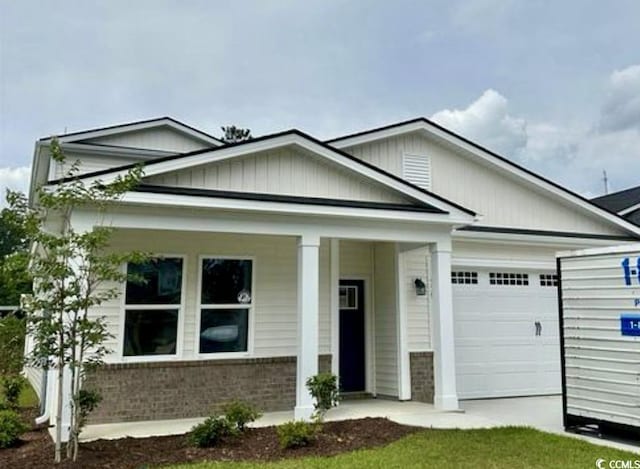 522 6th Ave S, North Myrtle Beach, SC 29582 - view of front facade with a garage, brick siding, and covered porch