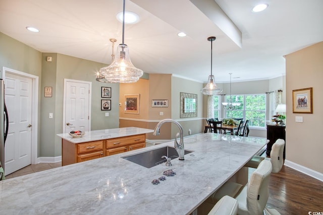 kitchen featuring a sink, baseboards, a center island, light stone countertops, and recessed lighting