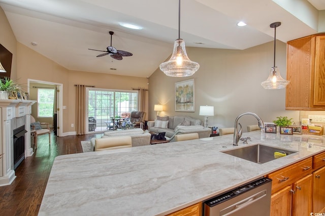 kitchen with a sink, stainless steel dishwasher, vaulted ceiling, ceiling fan, and light stone countertops