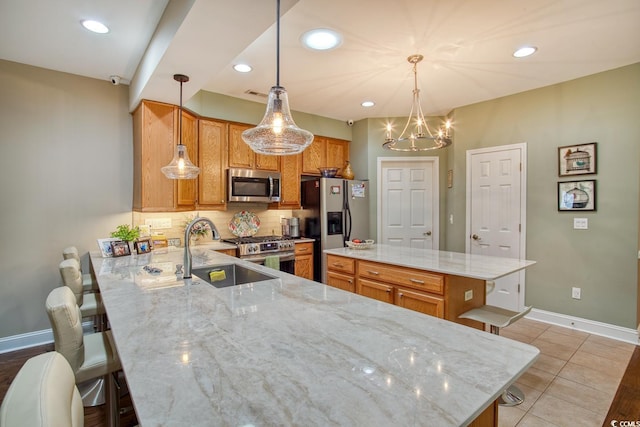 kitchen with stainless steel appliances, a sink, backsplash, a peninsula, and light stone counters