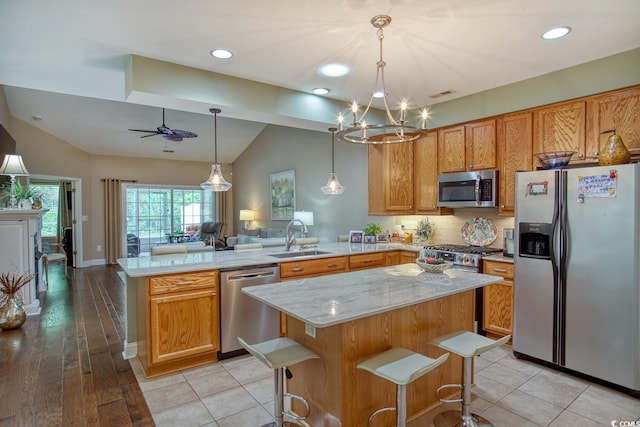 kitchen featuring stainless steel appliances, a peninsula, a sink, open floor plan, and lofted ceiling