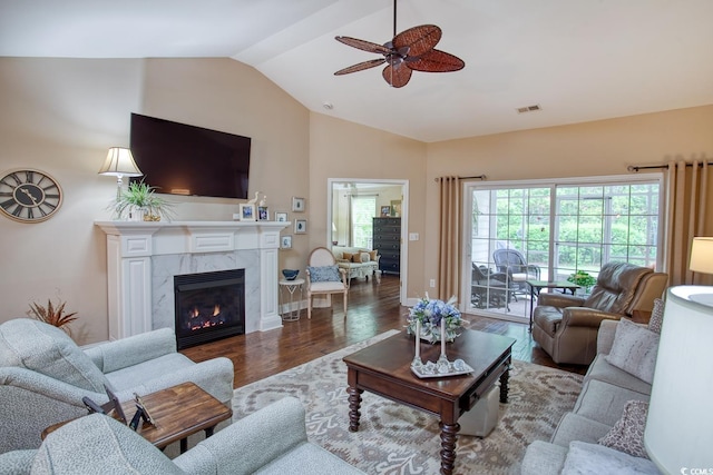 living room featuring lofted ceiling, a ceiling fan, wood finished floors, a premium fireplace, and baseboards