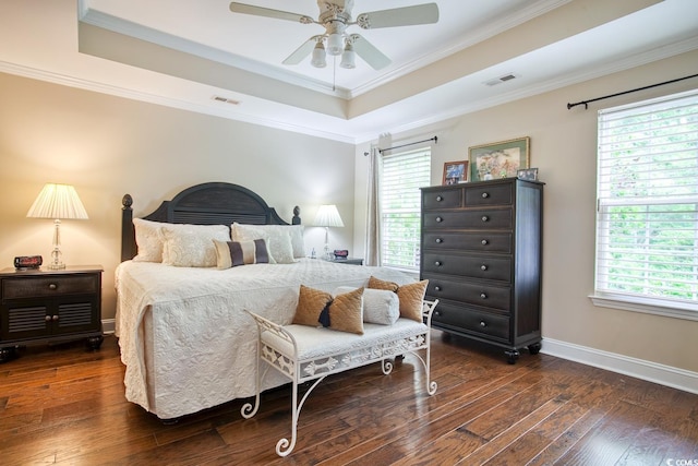bedroom with dark wood-type flooring, ornamental molding, a tray ceiling, baseboards, and a ceiling fan
