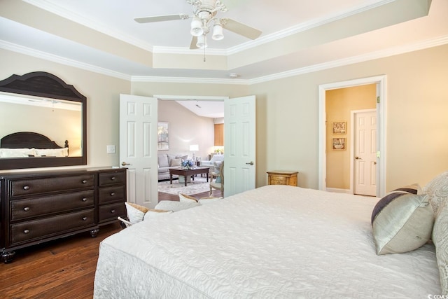 bedroom featuring a raised ceiling, dark wood finished floors, ornamental molding, and a ceiling fan
