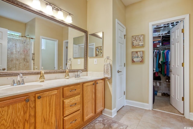 full bath with tile patterned flooring, double vanity, a walk in closet, and baseboards