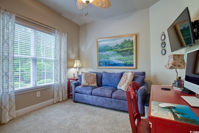 carpeted office space featuring a ceiling fan and baseboards