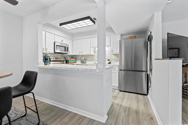 10301 N Kings Hwy Unit 10-4, Myrtle Beach, SC 29572 - kitchen with stainless steel appliances, light wood finished floors, white cabinets, and backsplash