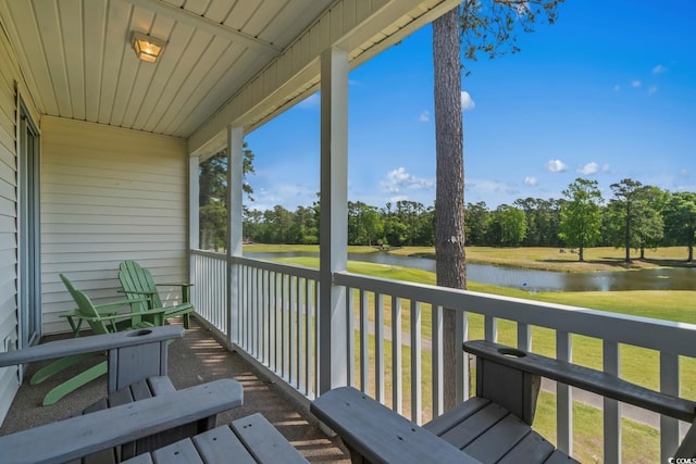 balcony with a water view and view of wooded area