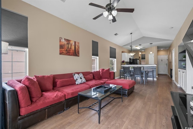 living area with lofted ceiling, ceiling fan, and light wood-style flooring