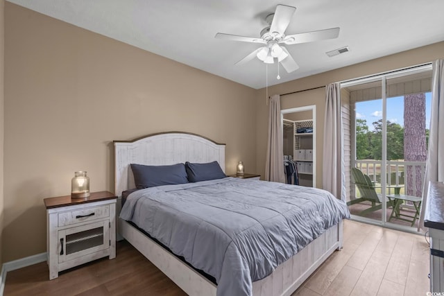 bedroom with wood finished floors, access to exterior, a walk in closet, a ceiling fan, and a closet